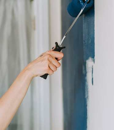 Person painting a wall dark blue